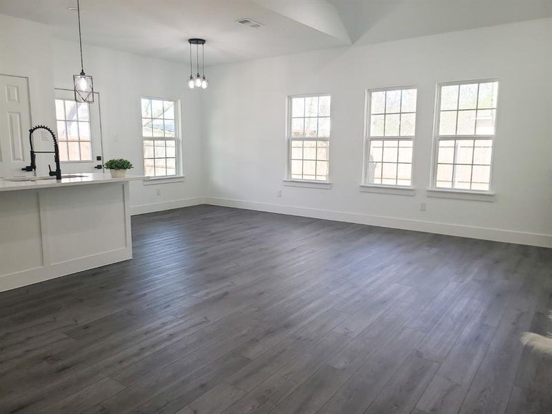 Bright living space featuring wood-finish flooring, vaulted ceilings, and white walls Bright living space featuring wood-finish flooring, vaulted ceilings, and white walls
