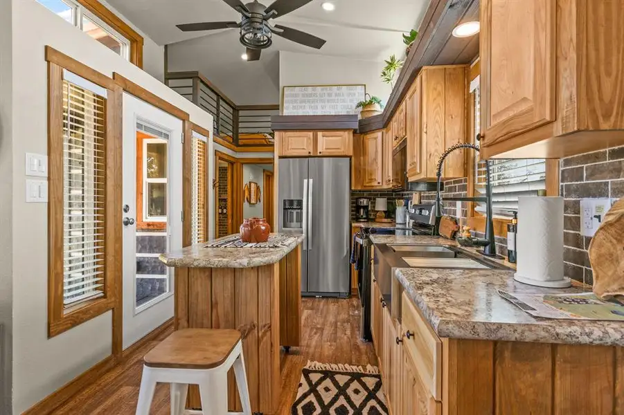Kitchen with stainless steel fridge, a kitchen island, black range with electric cooktop, dark wood-style floors, and vaulted ceiling