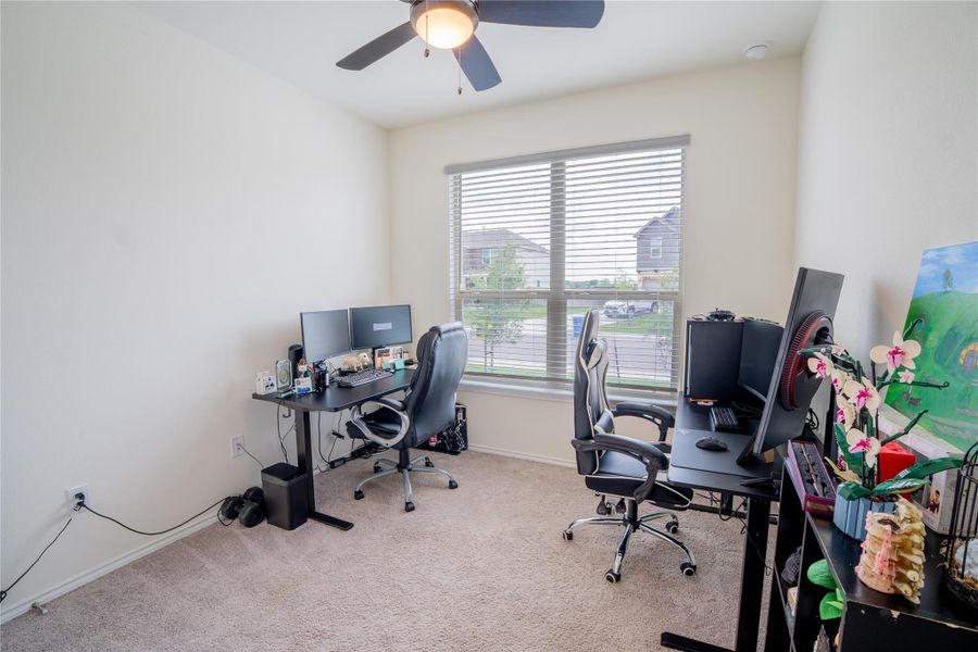 Carpeted interior room featuring a window with horizontal blinds, a ceiling fan with integrated lighting, and neutral wall tones Carpeted interior room featuring a window with horizontal blinds, a ceiling fan with integrated lighting, and neutral wall tones