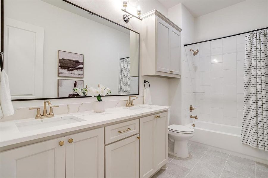 Full bathroom featuring gold hardware, tile flooring, Quart countertops, vanity, toilet, and shower / tub combo with built in cabinetry