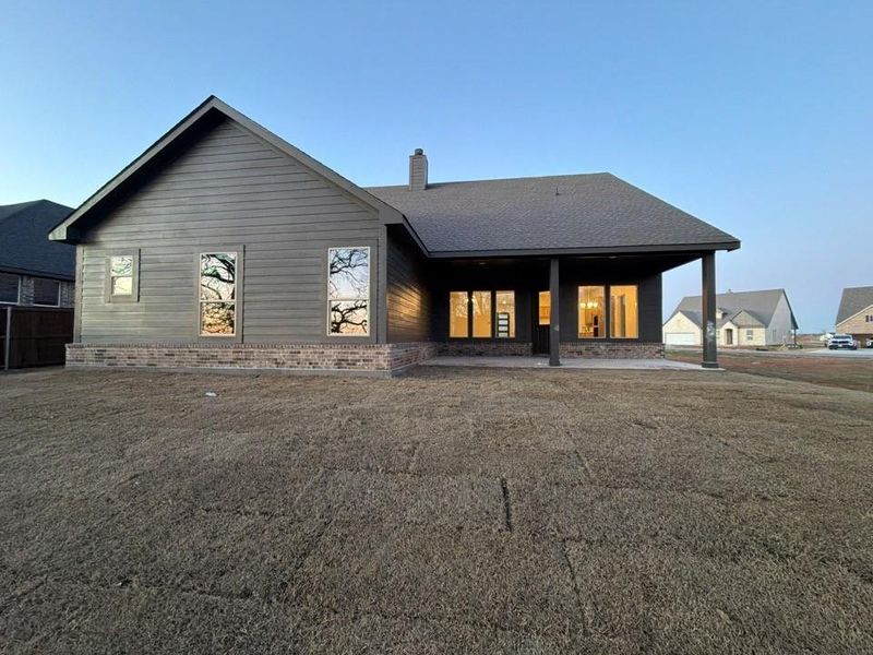 Rear view of house with a chimney, a patio area, a yard, and brick siding