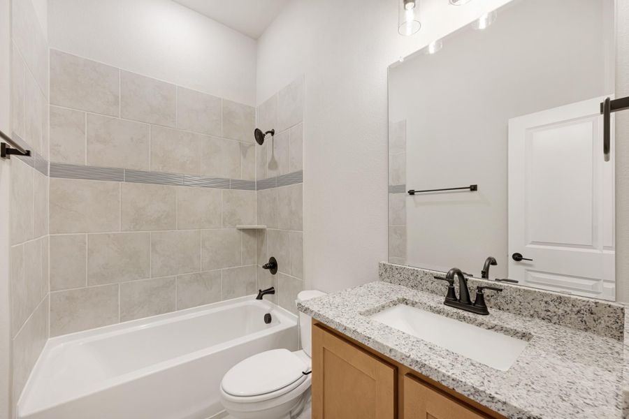 Bathroom with tiled tub-shower combo, granite vanity countertop, and dark bronze fixtures