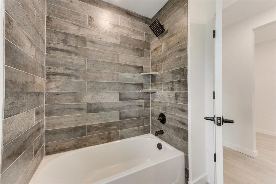 Bathroom featuring hardwood / wood-style flooring and tiled shower / bath