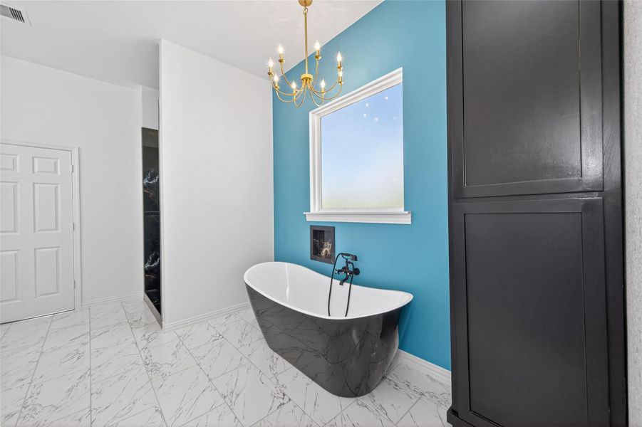Elegant primary bathroom with dual sinks, custom cabinetry, a freestanding soaking tub, and walk-in shower.