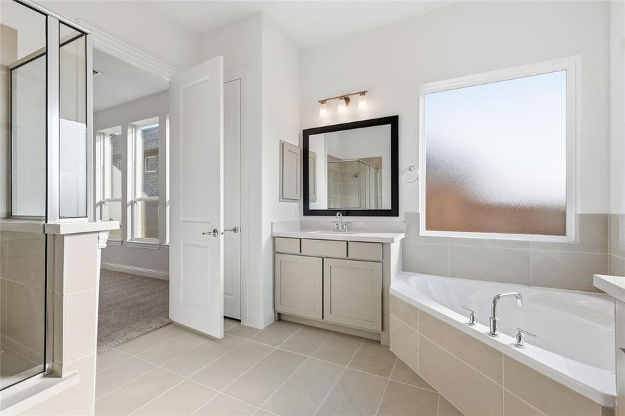 Full bath featuring a shower stall, a garden tub, vanity, and light tile patterned flooring