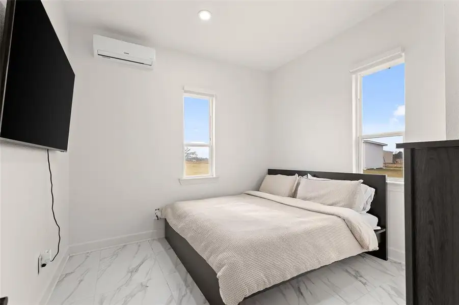Bedroom featuring light marble finish flooring, an AC wall unit, and recessed lighting