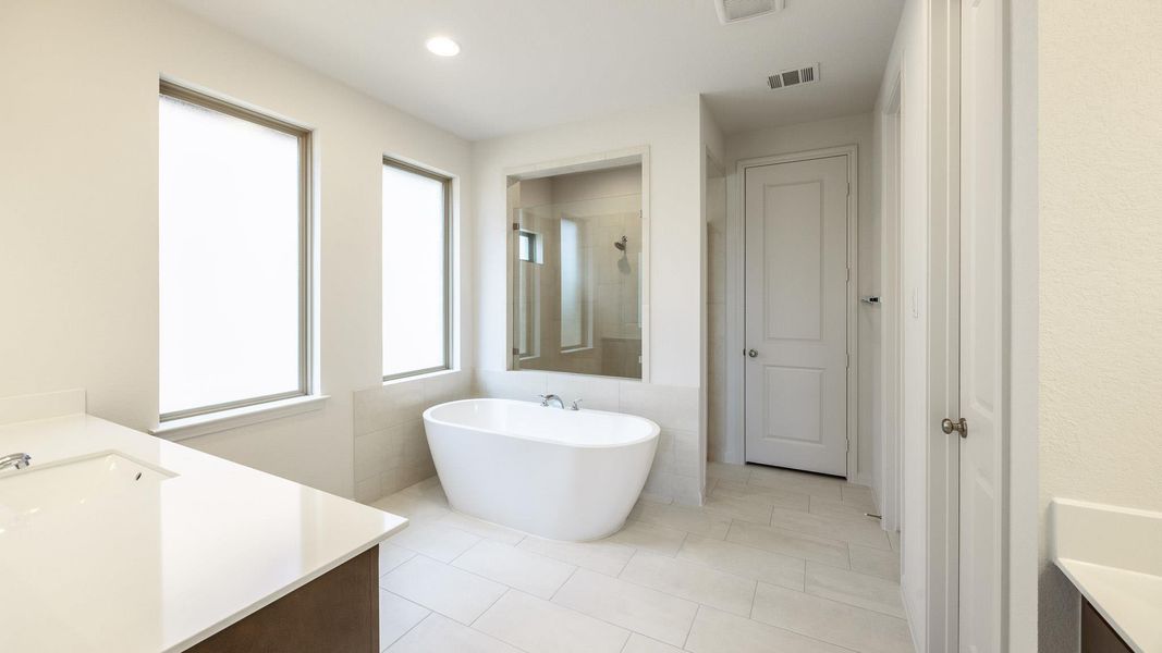 Full bath with a freestanding tub, vanity, tiled shower, light tile patterned floors, and recessed lighting Full bath with a freestanding tub, vanity, tiled shower, light tile patterned floors, and recessed lighting