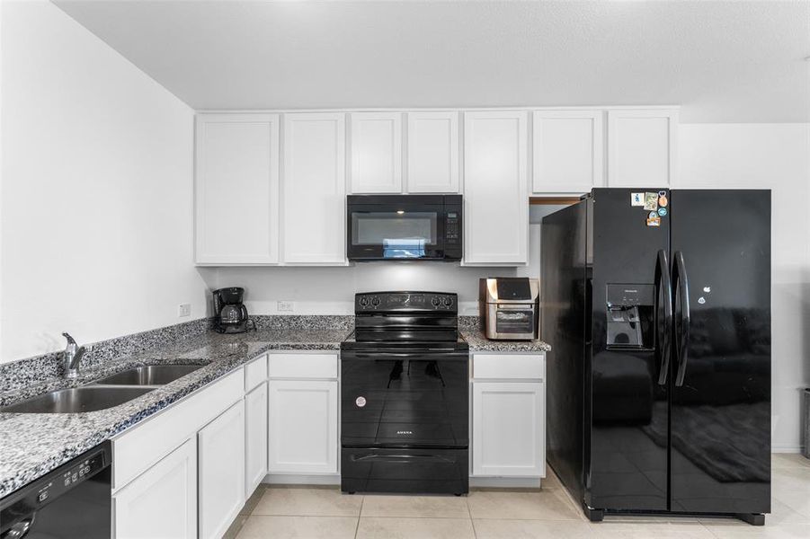 Kitchen featuring black appliances and white cabinetry Kitchen featuring black appliances and white cabinetry