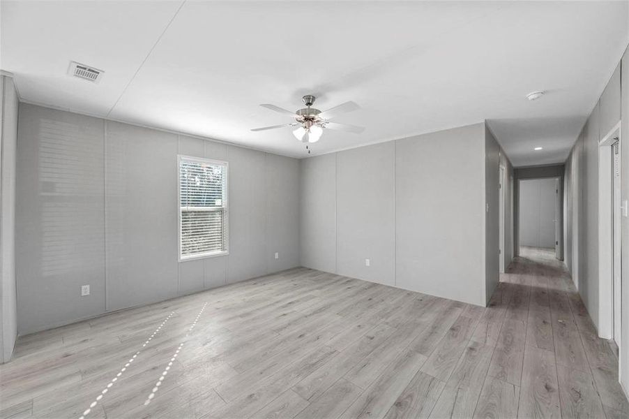 Empty room featuring visible vents, light wood-type flooring, and ceiling fan