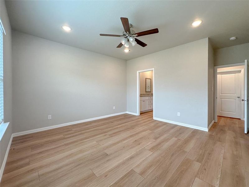 Unfurnished bedroom with ceiling fan, light hardwood / wood-style floors, and ensuite bath