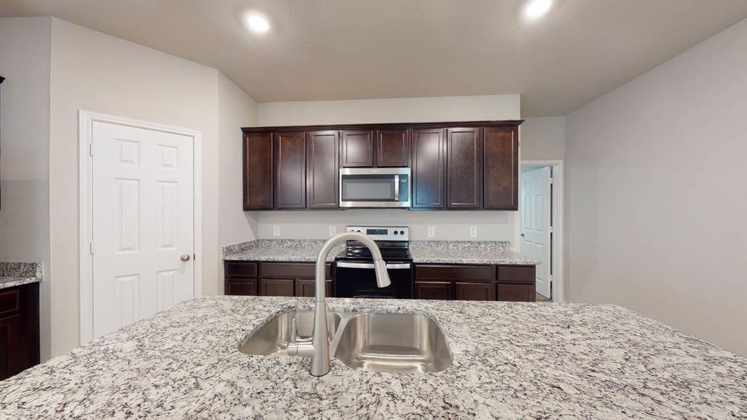 A well-appointed kitchen showcasing a spacious island with a double sink and a modern faucet. A well-appointed kitchen showcasing a spacious island with a double sink and a modern faucet.