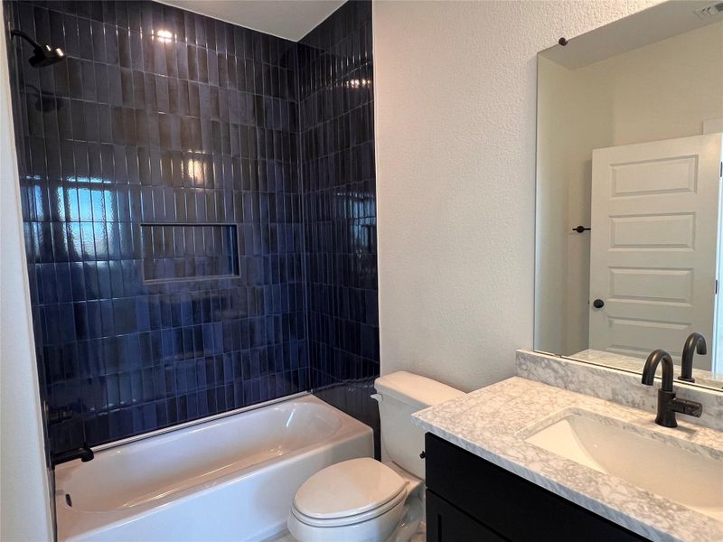 Bathroom with a textured wall, vanity, and shower / bath combination