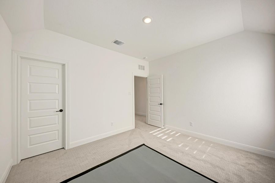 Unfurnished bedroom with vaulted ceiling and carpet floors