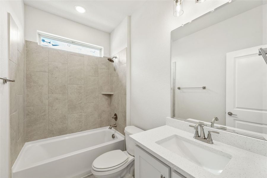 Bathroom with tiled shower-tub combo, white vanity with quartz countertop, and toilet Bathroom with tiled shower-tub combo, white vanity with quartz countertop, and toilet