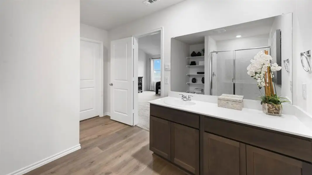 Bathroom vanity with a single basin sink and white countertop, dark wood-finish cabinetry, and a large wall-mounted mirror Bathroom vanity with a single basin sink and white countertop, dark wood-finish cabinetry, and a large wall-mounted mirror