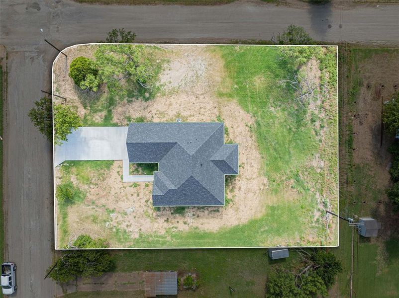 Property featuring a gray shingled roof, a concrete driveway, and an expansive corner lot