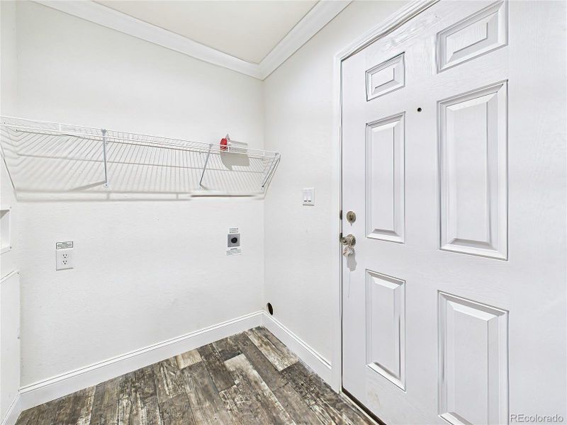 Dedicated laundry space with washer/dryer hookups and overhead shelving. Convenient access to back yard