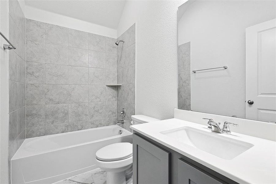 Full bathroom featuring tiled shower / bath combo, vanity, toilet, and tile patterned flooring