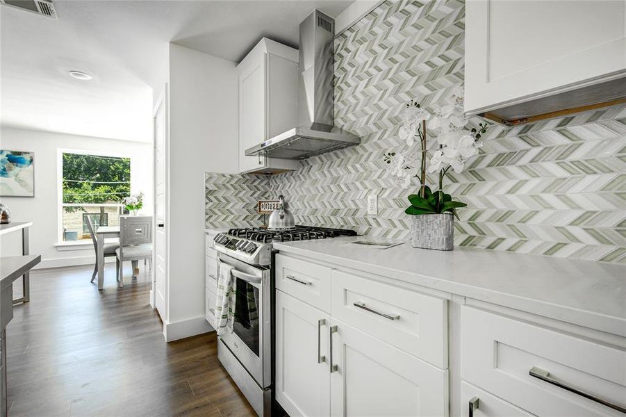 Kitchen with white cabinetry, dark hardwood / wood-style floors, wall chimney exhaust hood, backsplash, and gas range