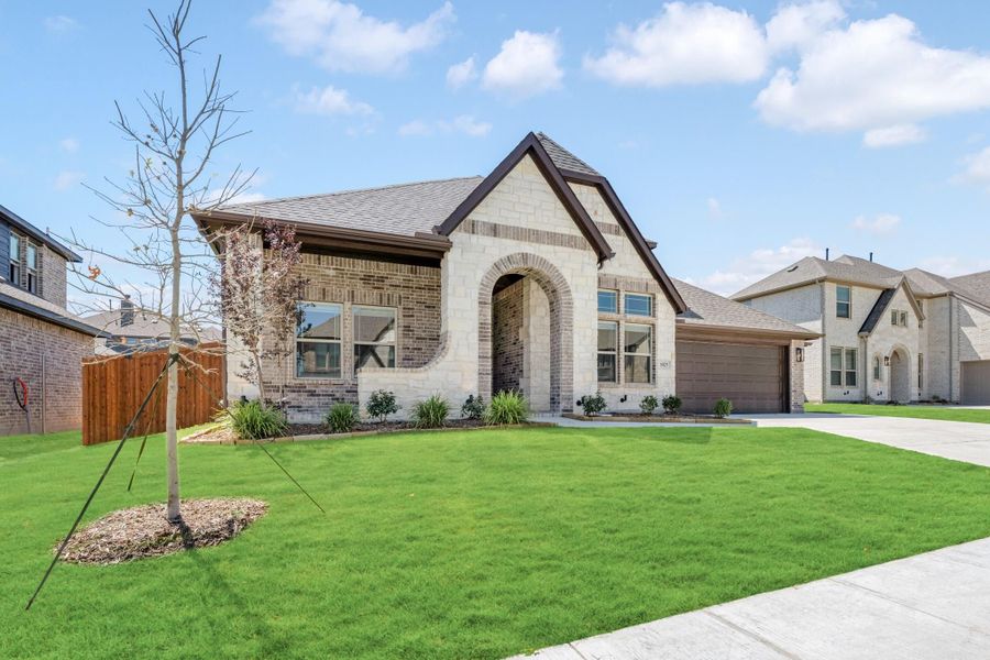 Single-story home with stone and brick exterior, arched entry, two-car garage, and green front lawn