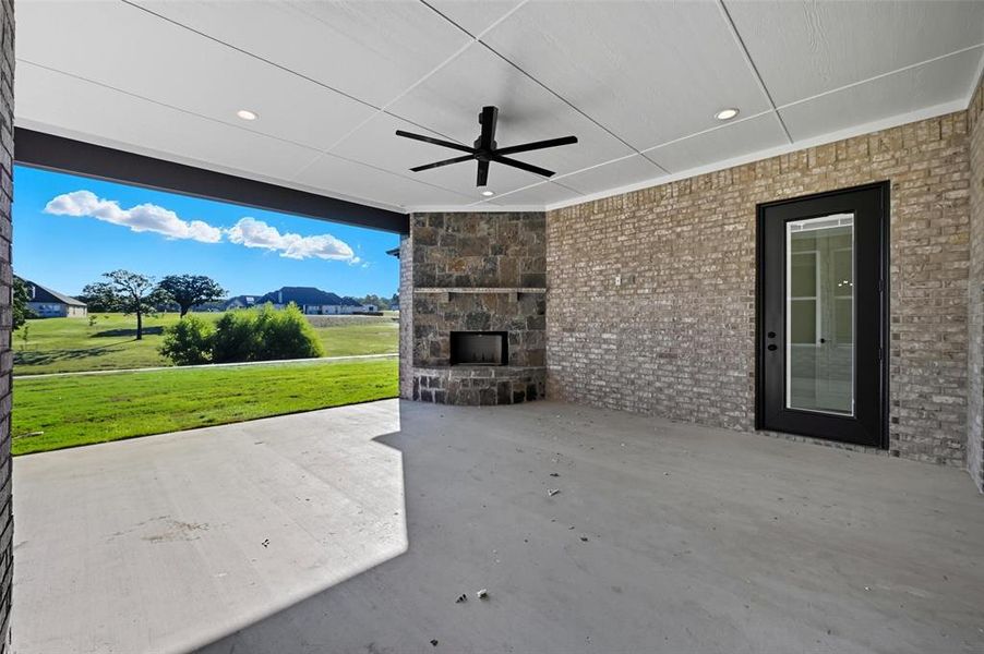 View of patio featuring a ceiling fan, an outdoor stone fireplace, and a residential view View of patio featuring a ceiling fan, an outdoor stone fireplace, and a residential view
