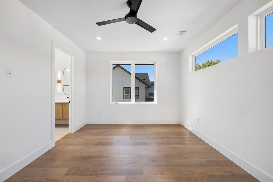 Unfurnished bedroom with light wood-type flooring, a ceiling fan, recessed lighting, and ensuite bath Unfurnished bedroom with light wood-type flooring, a ceiling fan, recessed lighting, and ensuite bath