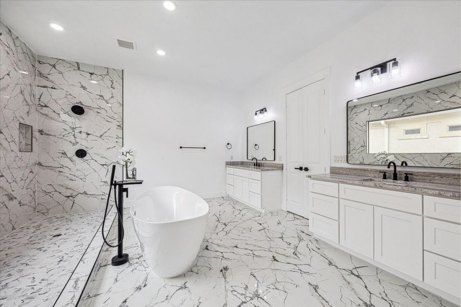 The primary bathroom is light-filled and luxurious, featuring elegant marble surfaces, dual vanities, two spacious showers, and a relaxing soaking tub, creating a spa-like retreat.