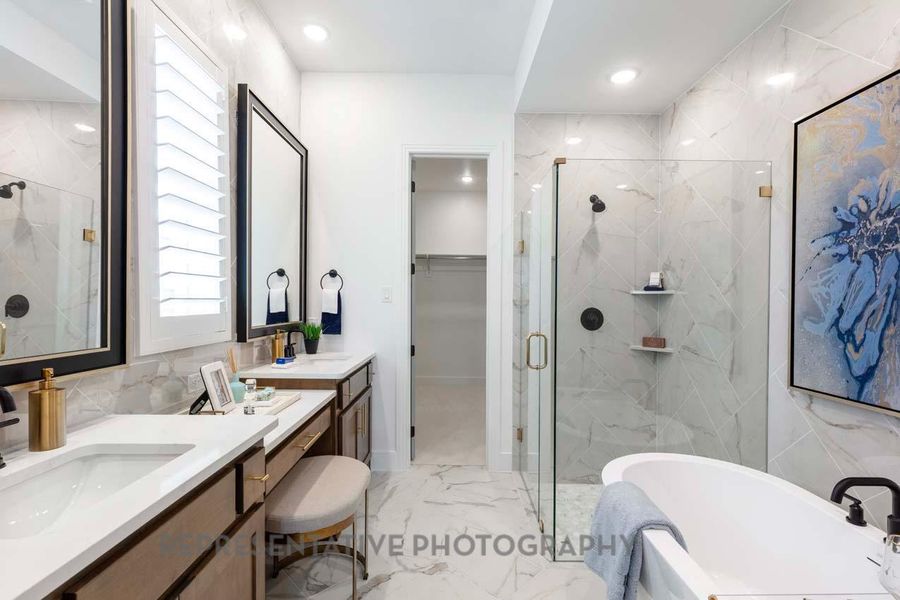 Full bath featuring marble look tiles, a marble finish shower, a freestanding bath, vanity, and a walk in closet Full bath featuring marble look tiles, a marble finish shower, a freestanding bath, vanity, and a walk in closet