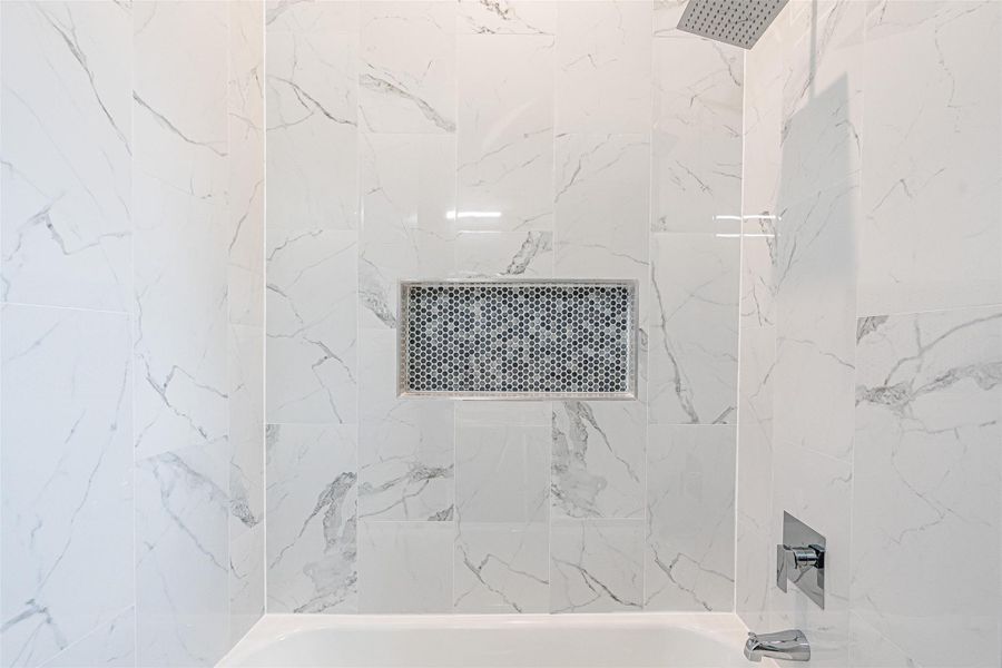 A sleek, tiled tub and shower combination features a convenient recessed niche and contemporary fixtures. A sleek, tiled tub and shower combination features a convenient recessed niche and contemporary fixtures.