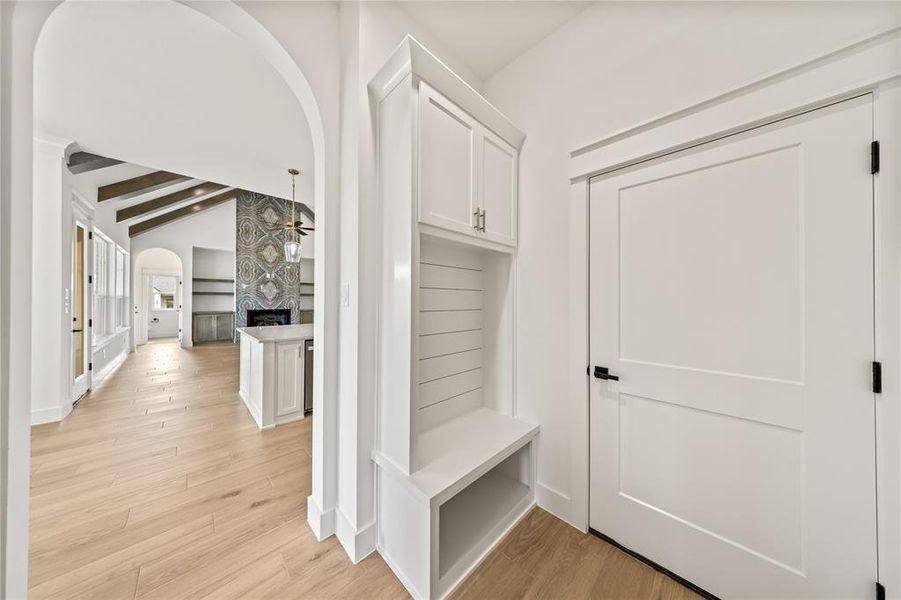 Entryway mudroom featuring built-in cabinetry, an integrated bench, and wall paneling
