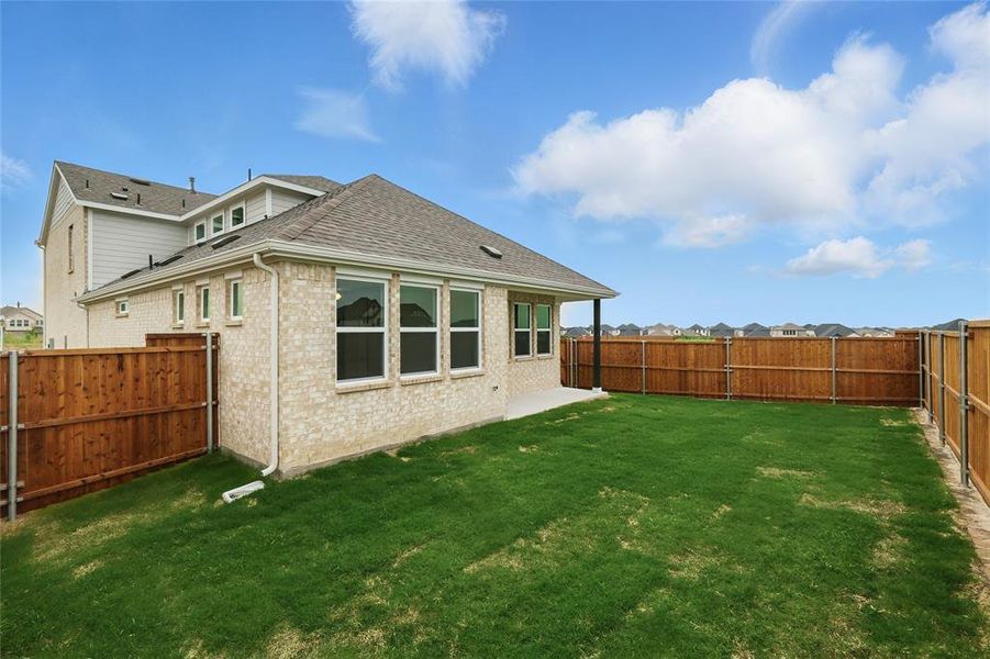 Back of property featuring a shingled roof, brick siding, and a fenced backyard Back of property featuring a shingled roof, brick siding, and a fenced backyard
