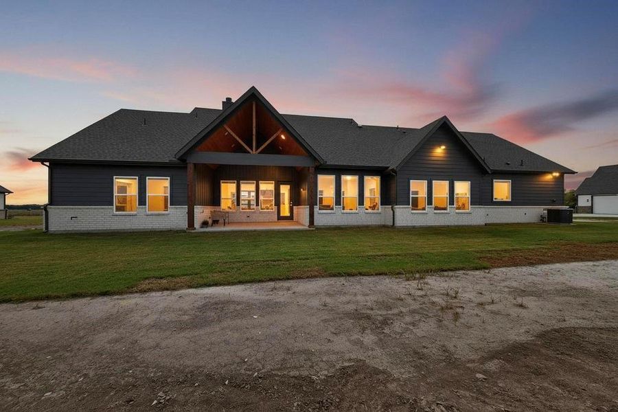Rear view of house with a patio area, a lawn, brick siding, and a chimney