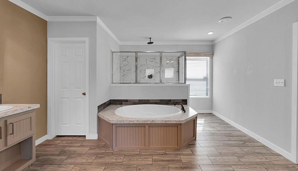 Full bathroom featuring wood tiled floors, a bath, crown molding, and a marble finish shower Full bathroom featuring wood tiled floors, a bath, crown molding, and a marble finish shower