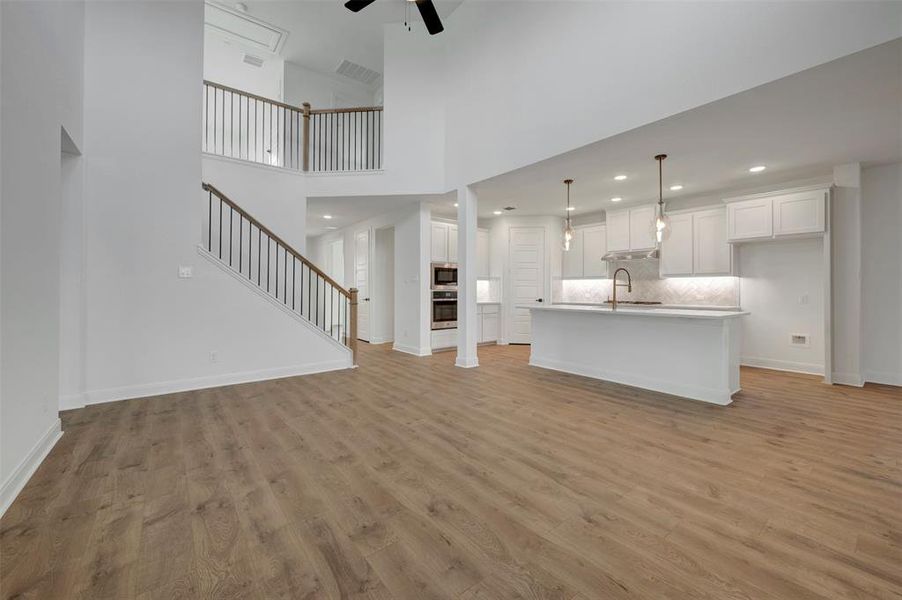 Unfurnished living room with a ceiling fan, light wood finished floors, a high ceiling, and recessed lighting