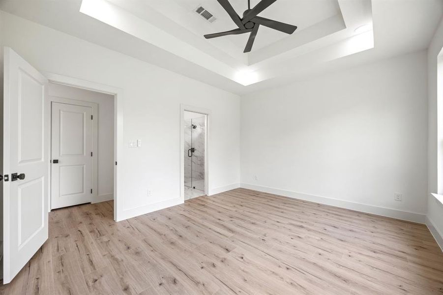 Unfurnished room with a raised ceiling, light wood-style floors, ceiling fan, and baseboards Unfurnished room with a raised ceiling, light wood-style floors, ceiling fan, and baseboards