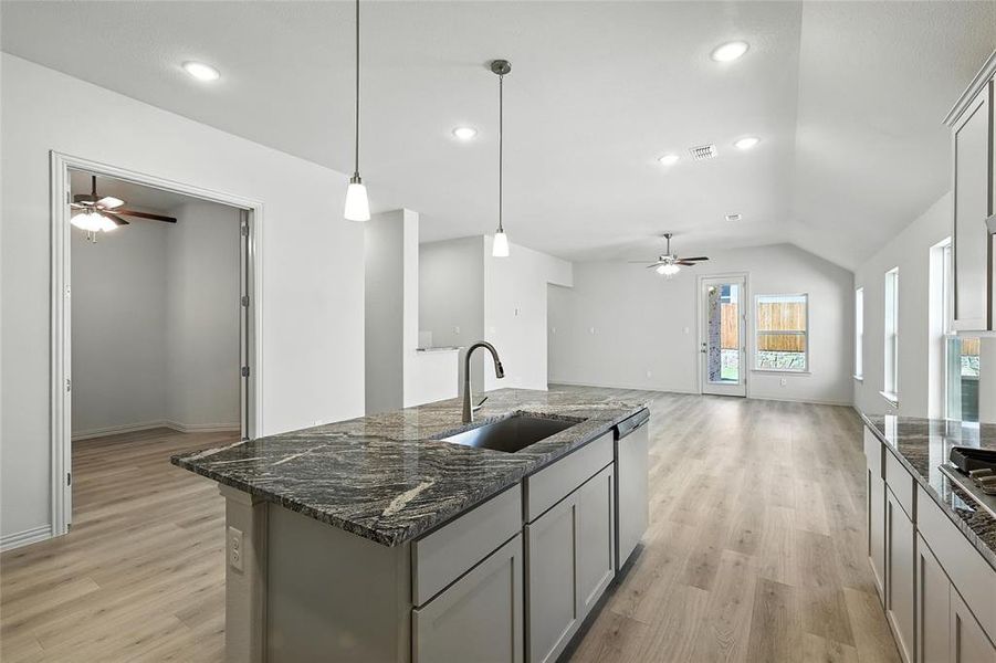 Kitchen with a ceiling fan, light wood-style floors, gray cabinets, lofted ceiling, and recessed lighting Kitchen with a ceiling fan, light wood-style floors, gray cabinets, lofted ceiling, and recessed lighting