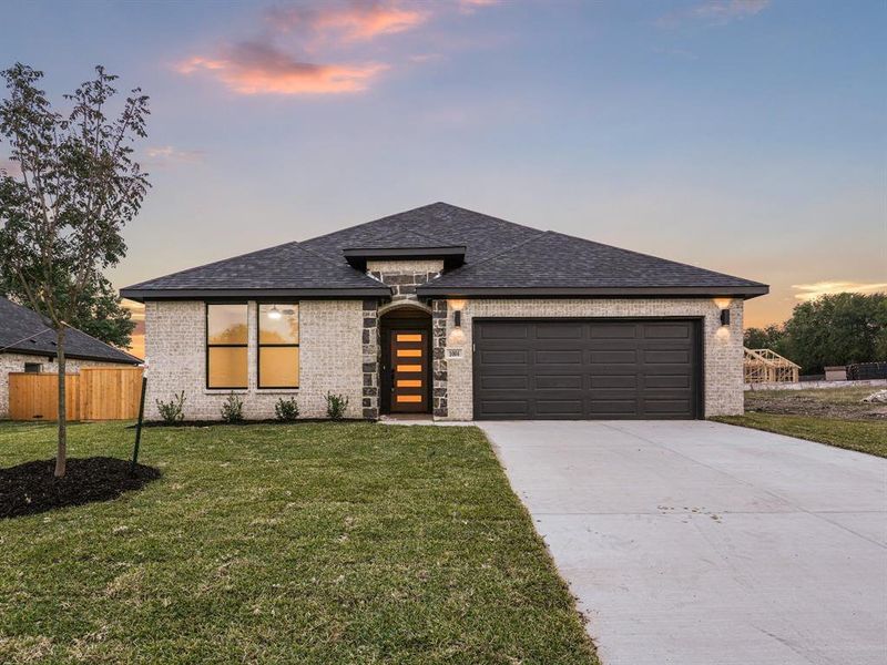 View of front of property featuring a lawn and a garage