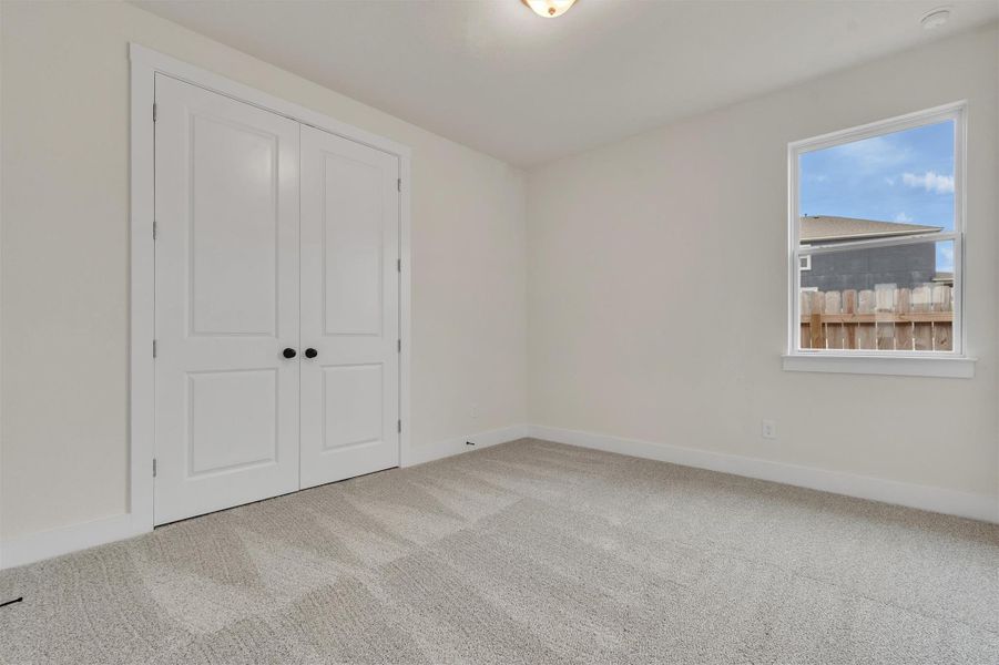 A well-lit bedroom features plush carpeting and a spacious closet.