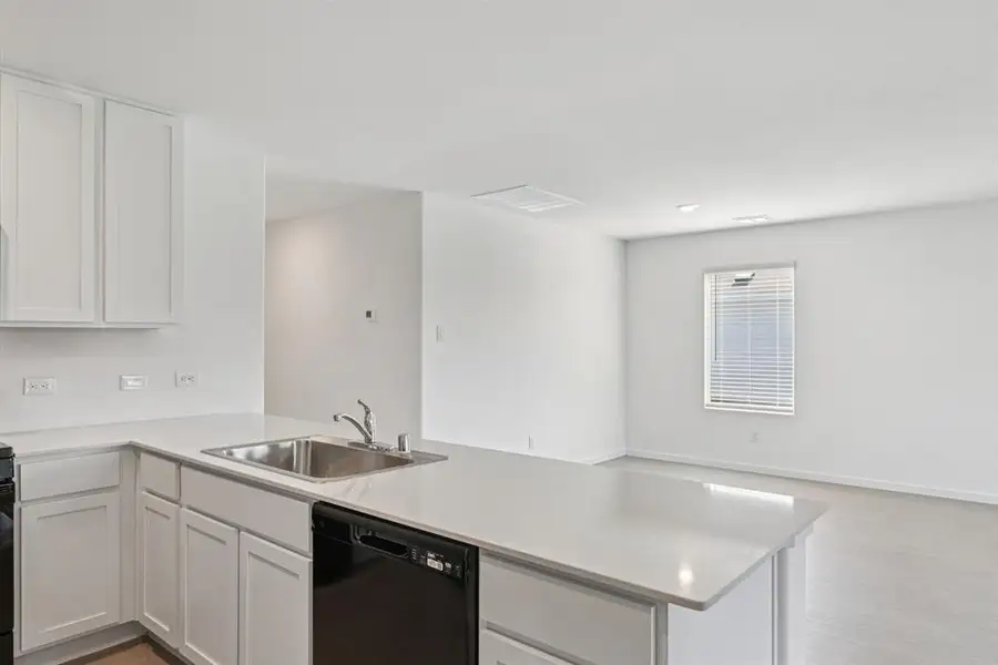 Kitchen with dishwasher, a peninsula, light countertops, and white cabinets