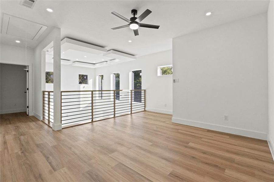 Empty room featuring attic access, light wood-style flooring, ceiling fan, a raised ceiling, and recessed lighting