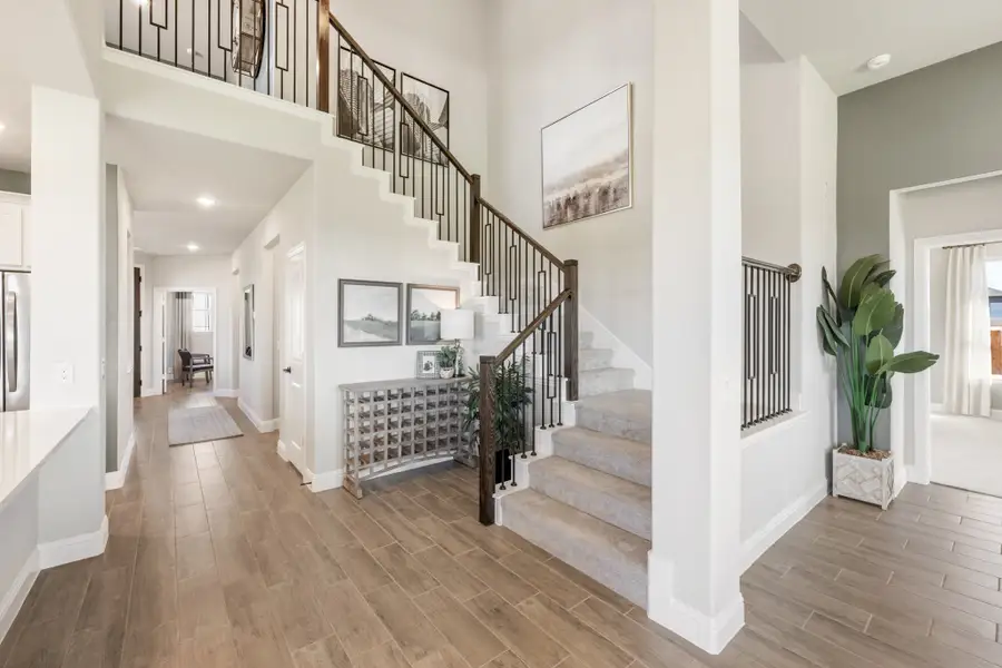 Two-story entryway with wood staircase, iron balusters, high ceilings, and wood-look tile floors