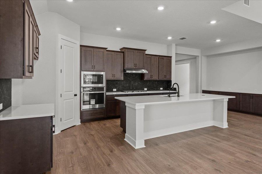 Kitchen with under cabinet range hood, stainless steel appliances, wood finished floors, a sink, and recessed lighting Kitchen with under cabinet range hood, stainless steel appliances, wood finished floors, a sink, and recessed lighting
