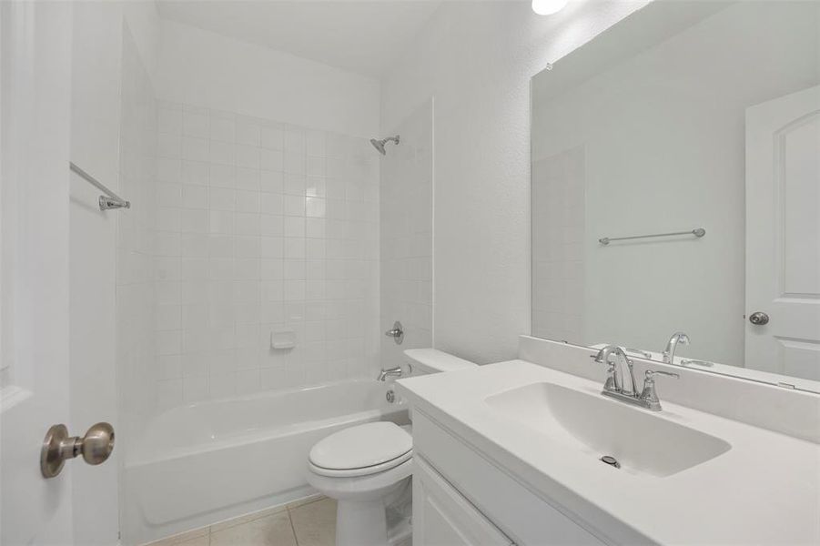 Full bathroom with tile patterned floors, vanity, toilet, and tiled shower / bath combo