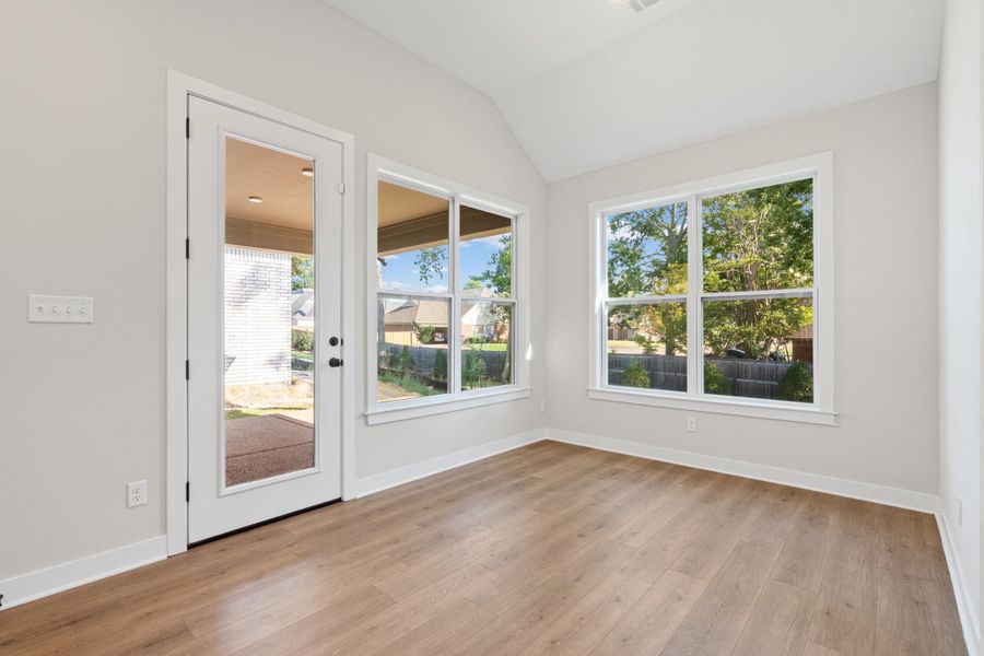 Vaulted ceiling, wood-finish flooring, white trim, glass-paneled exterior door, and multiple windows Vaulted ceiling, wood-finish flooring, white trim, glass-paneled exterior door, and multiple windows