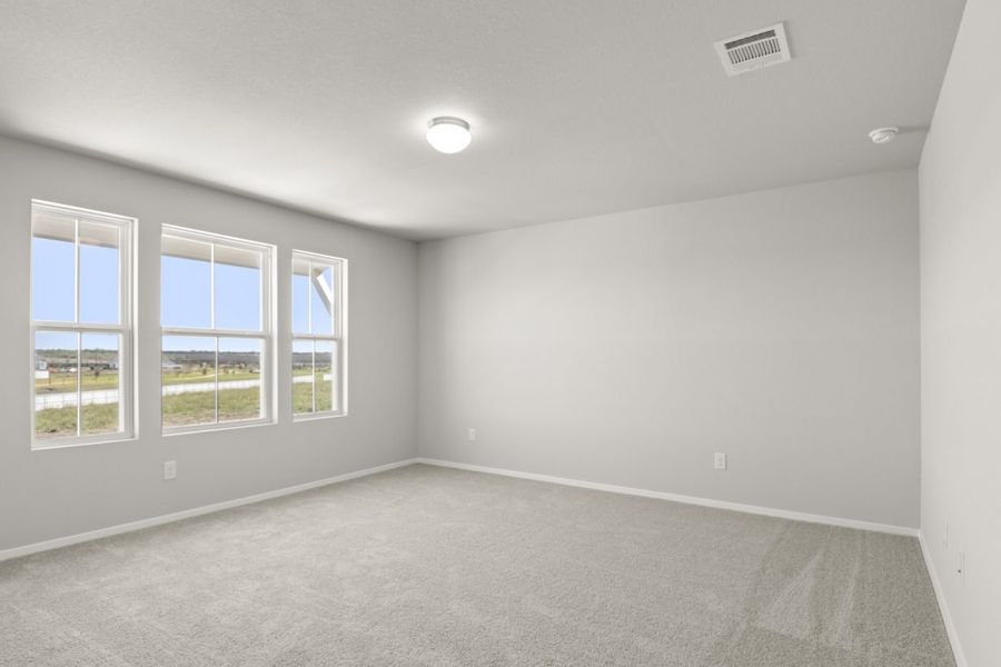 Image of a bedroom with tan carpeting, light grey walls, and three windows