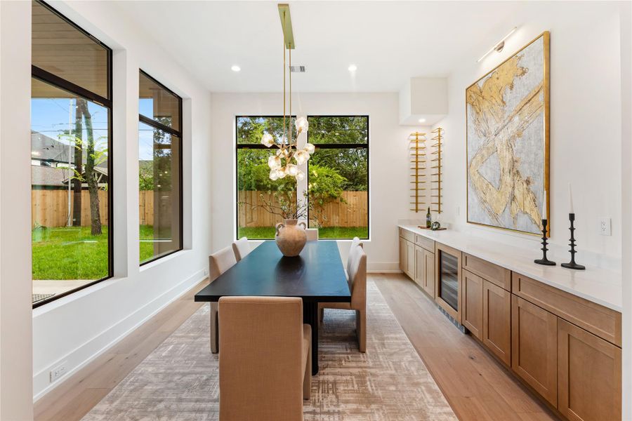 Beautiful dining room features soaring windows that create a bright, airy atmosphere by day, while the ornate chandelier transforms the space into an intimate and glamorous setting at night.