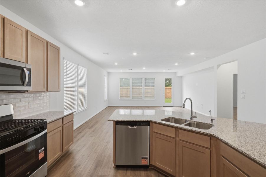 Featured here is the gorgeous granite countertops and the view looking out to the open concept living spaces and backyard views!