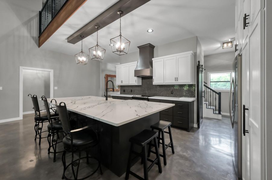 ample counter space, creating a clean and functional cooking area. Large island with a marble countertop and seating,