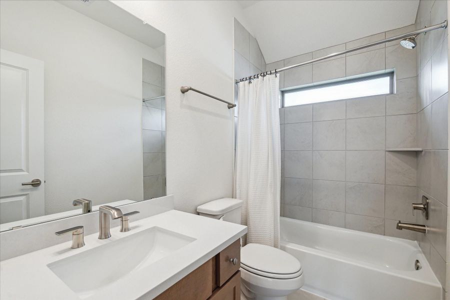 The upstairs secondary bathroom features a full-height tiled shower/tub combination for a clean, elegant look, conveniently situated between the two secondary bedrooms.