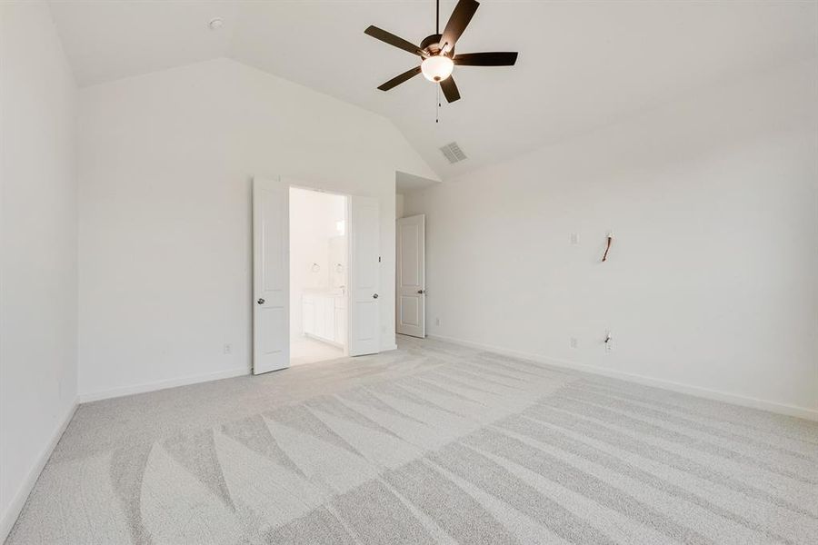 Unfurnished bedroom with light carpet, ceiling fan, lofted ceiling, and ensuite bath Unfurnished bedroom with light carpet, ceiling fan, lofted ceiling, and ensuite bath